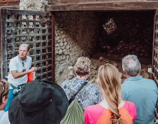 Tour group with archaeologist at Herculaneum site viewing ancient skeletons.