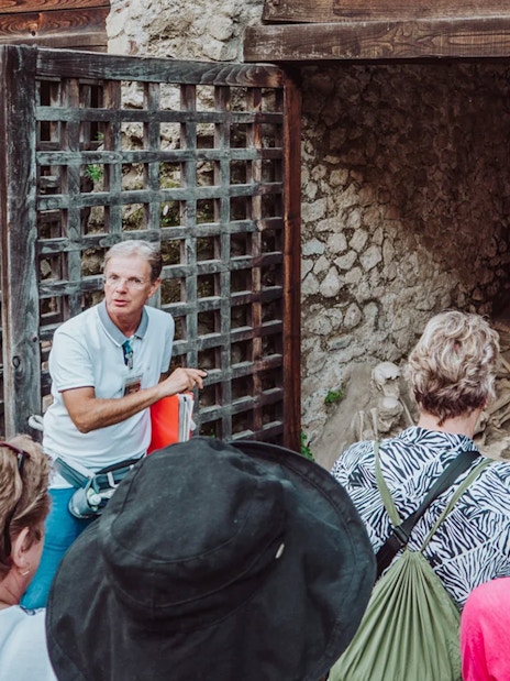 Tour group with archaeologist at Herculaneum site viewing ancient skeletons.