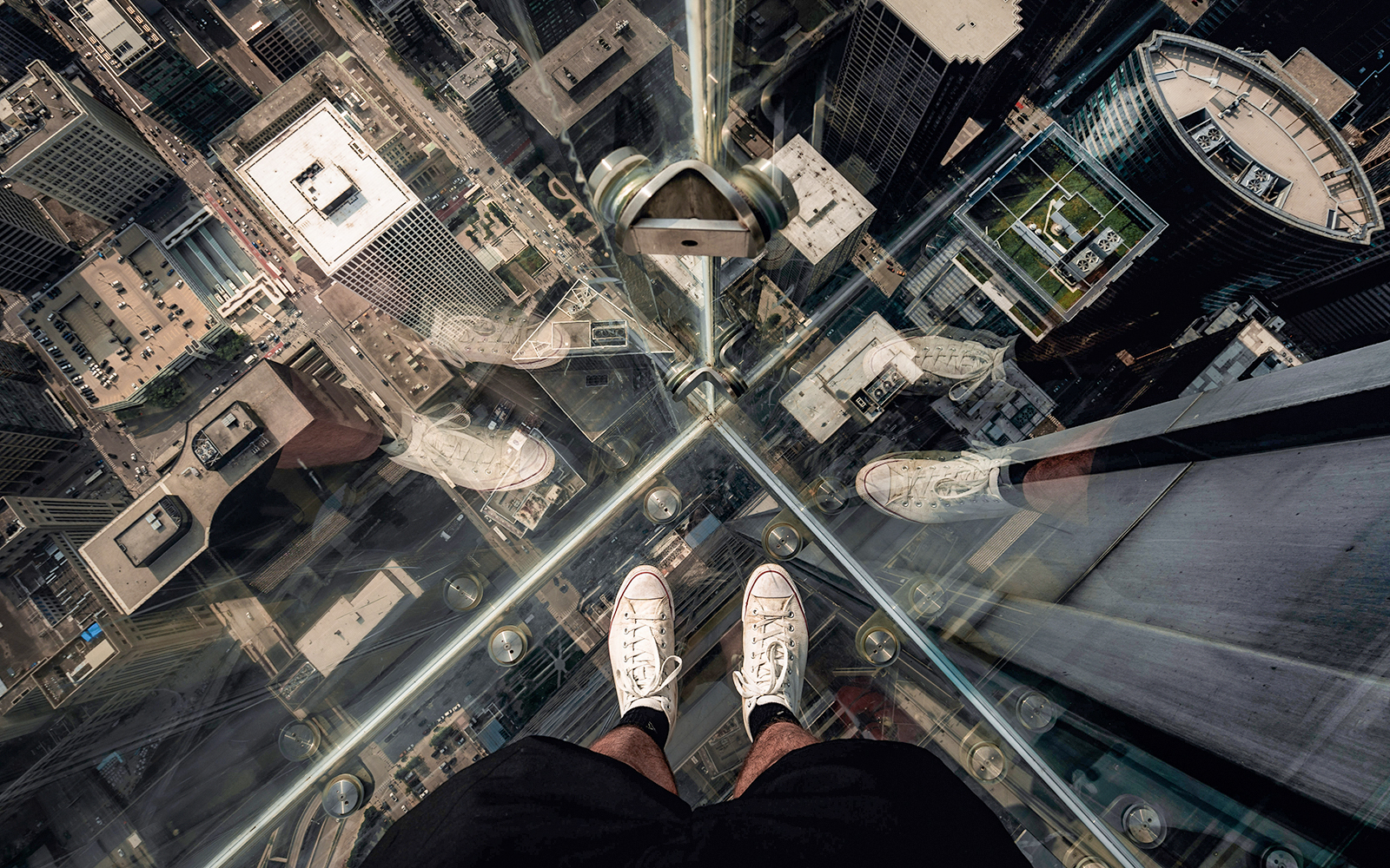 Guests standing on Chicago Skydeck glass ledge overlooking cityscape during architecture tour.