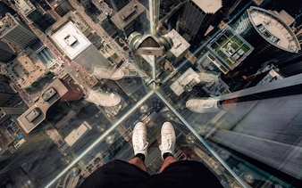 Guests standing on Chicago Skydeck glass ledge overlooking cityscape during architecture tour.