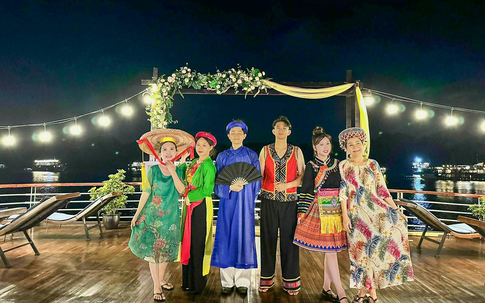 Guests in traditional attire at a fashion show on Amanda Luxury Cruise deck at night.