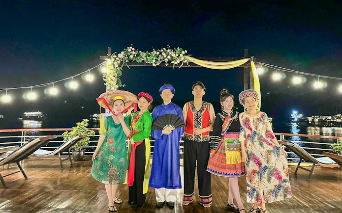 Guests in traditional attire at a fashion show on Amanda Luxury Cruise deck at night.