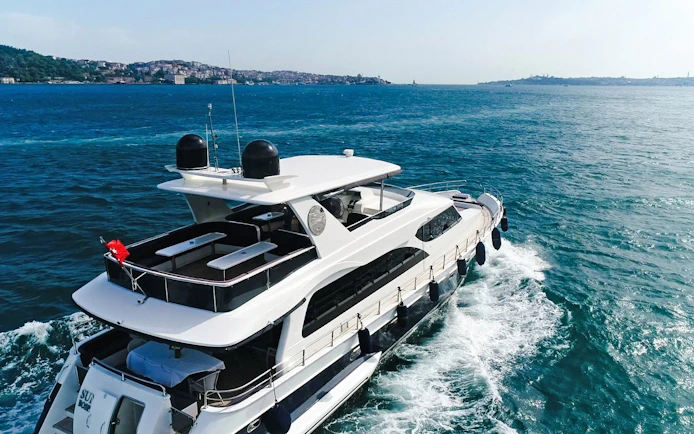 Yacht cruising on the Bosphorus with Istanbul skyline in the background.