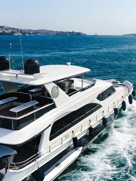 Yacht cruising on the Bosphorus with Istanbul skyline in the background.