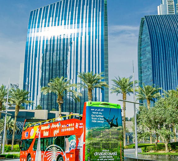 Open-top tour bus in Dubai with modern skyscrapers in the background.