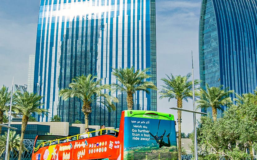 Open-top tour bus in Dubai with modern skyscrapers in the background.
