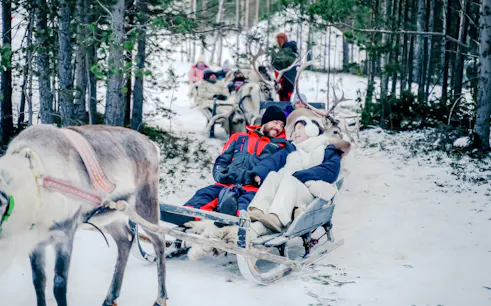 Guests enjoying a reindeer sled ride through snowy forest during Sámi Culture Experience.