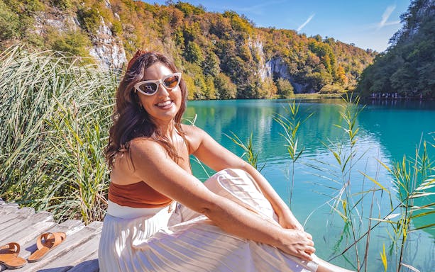 Visitor relaxing by the turquoise waters of Plitvice Lakes National Park, Croatia.
