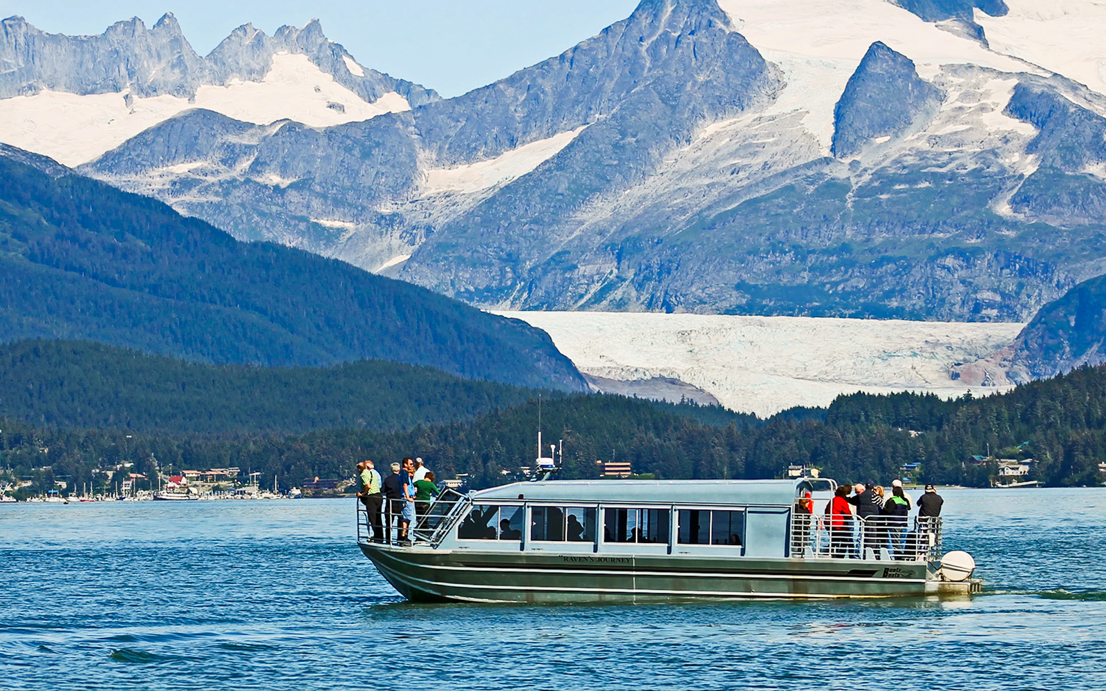 Boat with tourists on a whale watching tour in Juneau, Alaska, with mountains in the background.