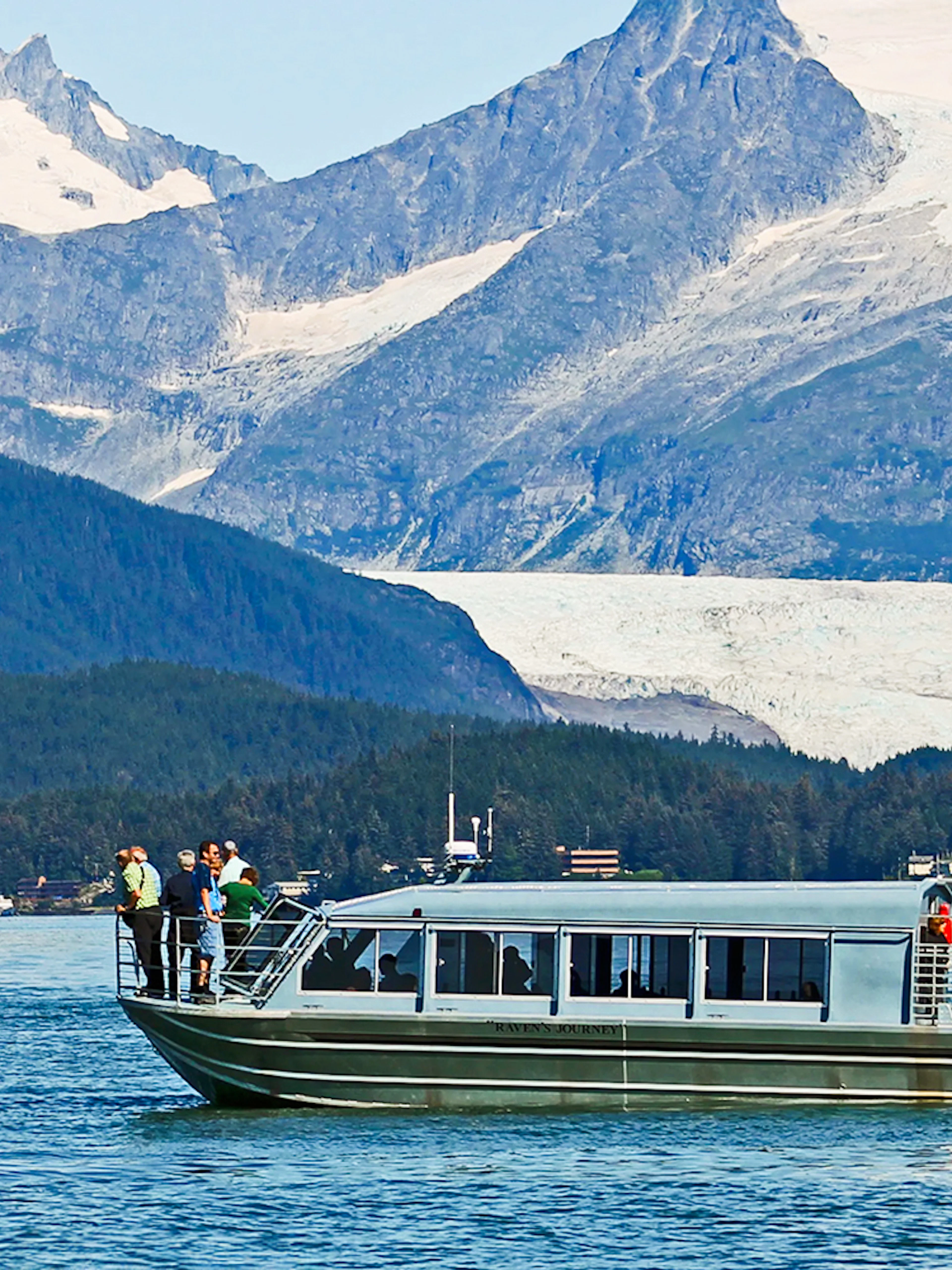 Boat with tourists on a whale watching tour in Juneau, Alaska, with mountains in the background.