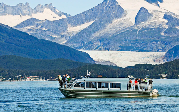 Boat with tourists on a whale watching tour in Juneau, Alaska, with mountains in the background.