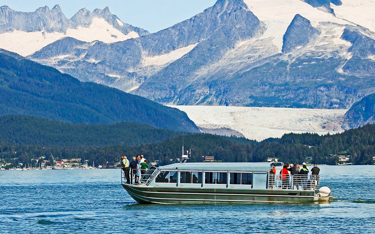 Boat with tourists on a whale watching tour in Juneau, Alaska, with mountains in the background.