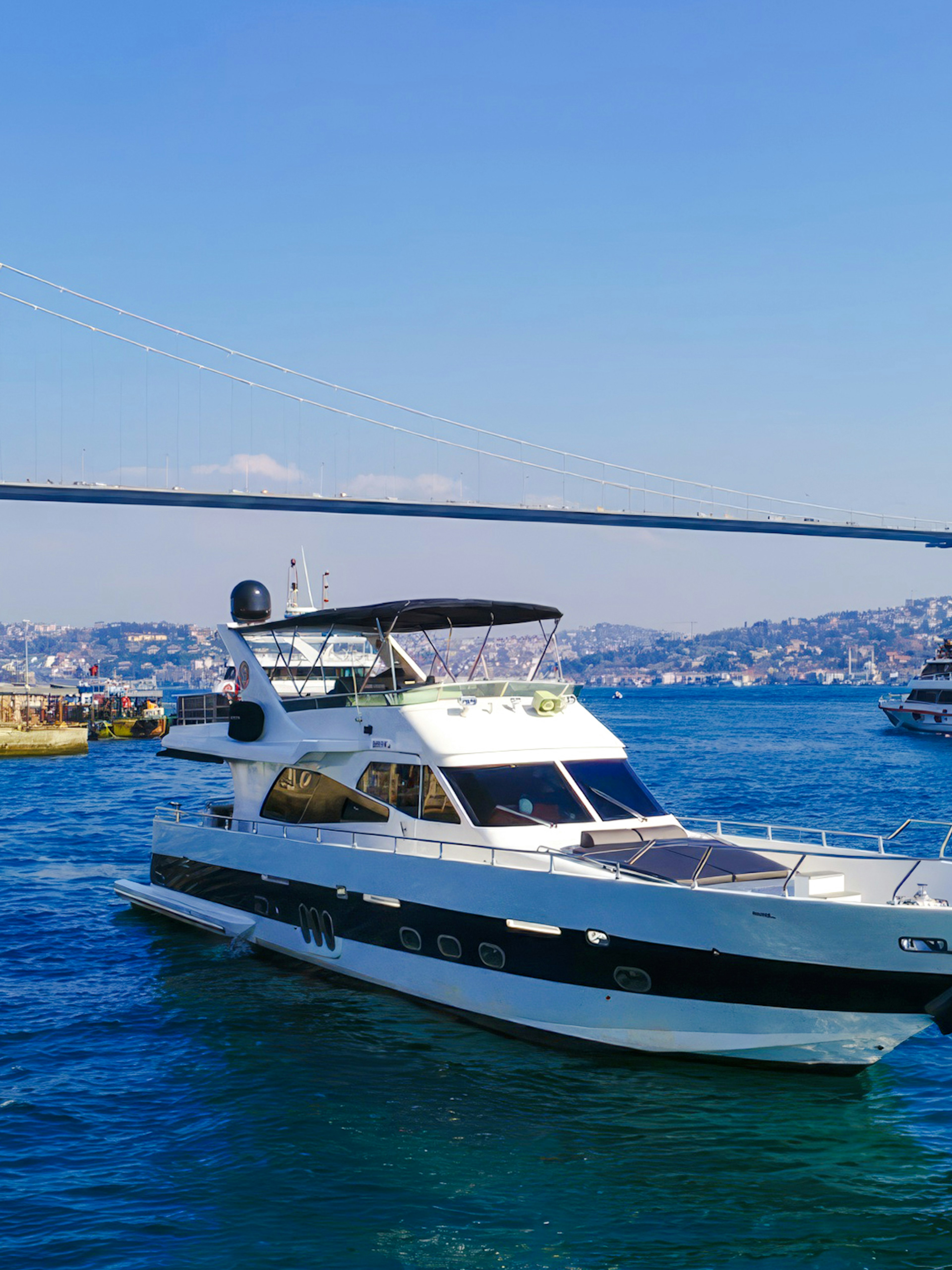 Luxury yacht cruising on the Bosphorus near Ortaköy Mosque, Istanbul.