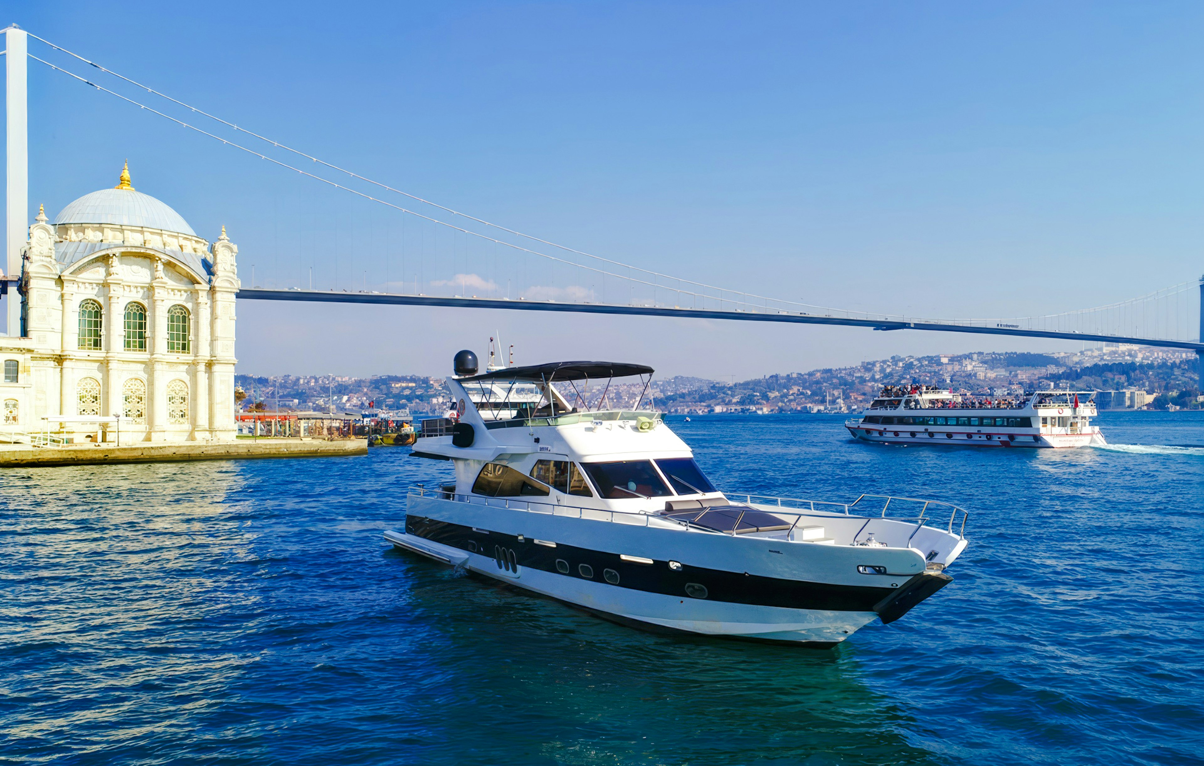 Luxury yacht cruising on the Bosphorus near Ortaköy Mosque, Istanbul.