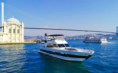 Luxury yacht cruising on the Bosphorus near Ortaköy Mosque, Istanbul.