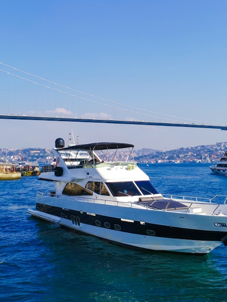 Luxury yacht cruising on the Bosphorus near Ortaköy Mosque, Istanbul.