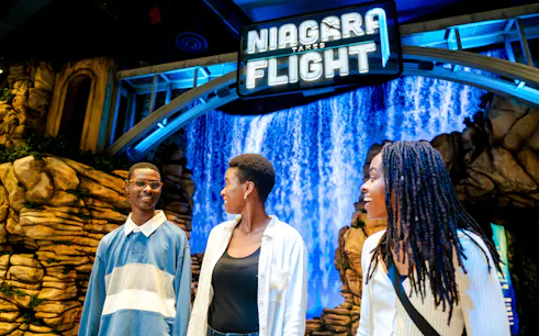 Visitors enjoying Niagara Takes Flight attraction in Canada with waterfall backdrop.