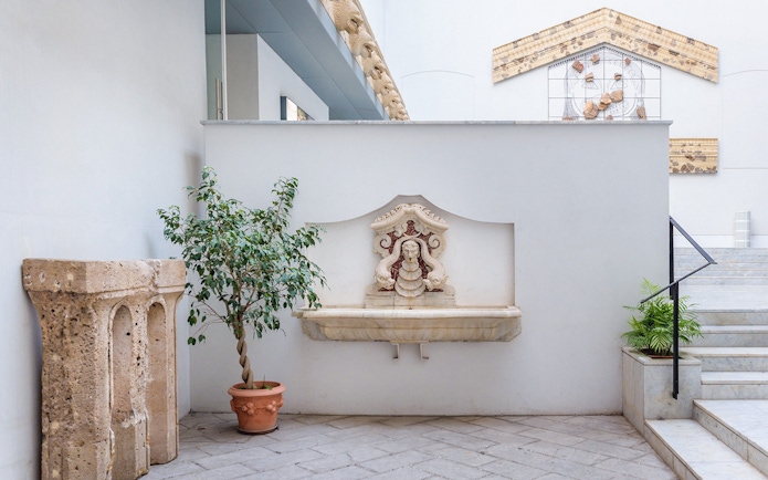 Courtyard with stone fountain and potted plants at Antonino Salinas Archaeological Museum.