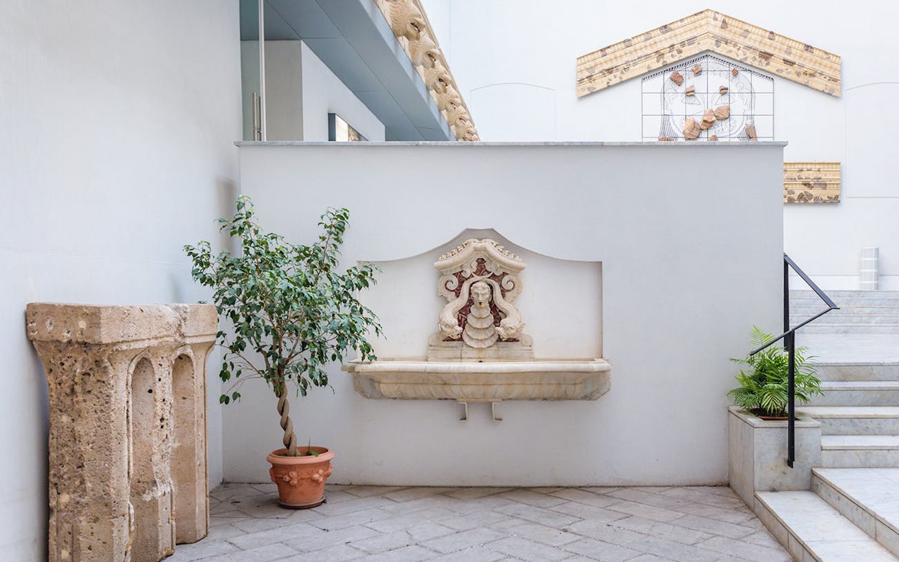 Courtyard with stone fountain and potted plants at Antonino Salinas Archaeological Museum.