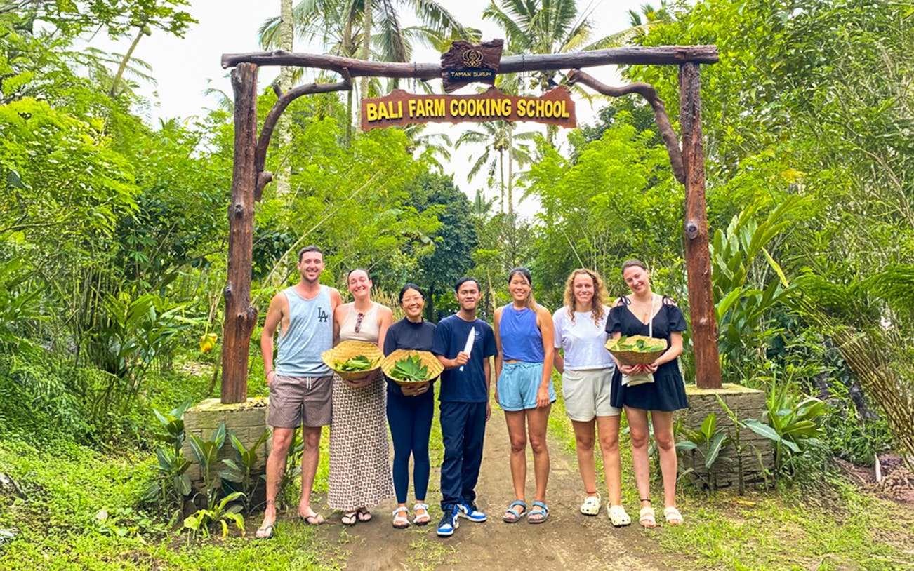 Group holding baskets at Bali Farm Cooking School entrance.