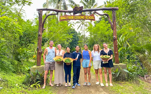 Group holding baskets at Bali Farm Cooking School entrance.