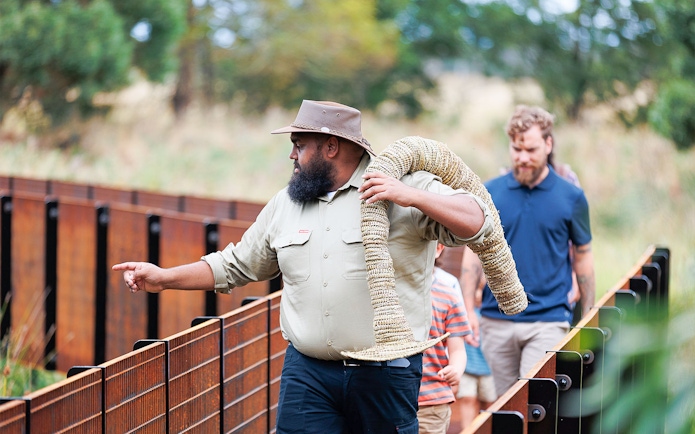 Guide leading Tungatt Mirring Stone Country tour with group on wooden walkway.