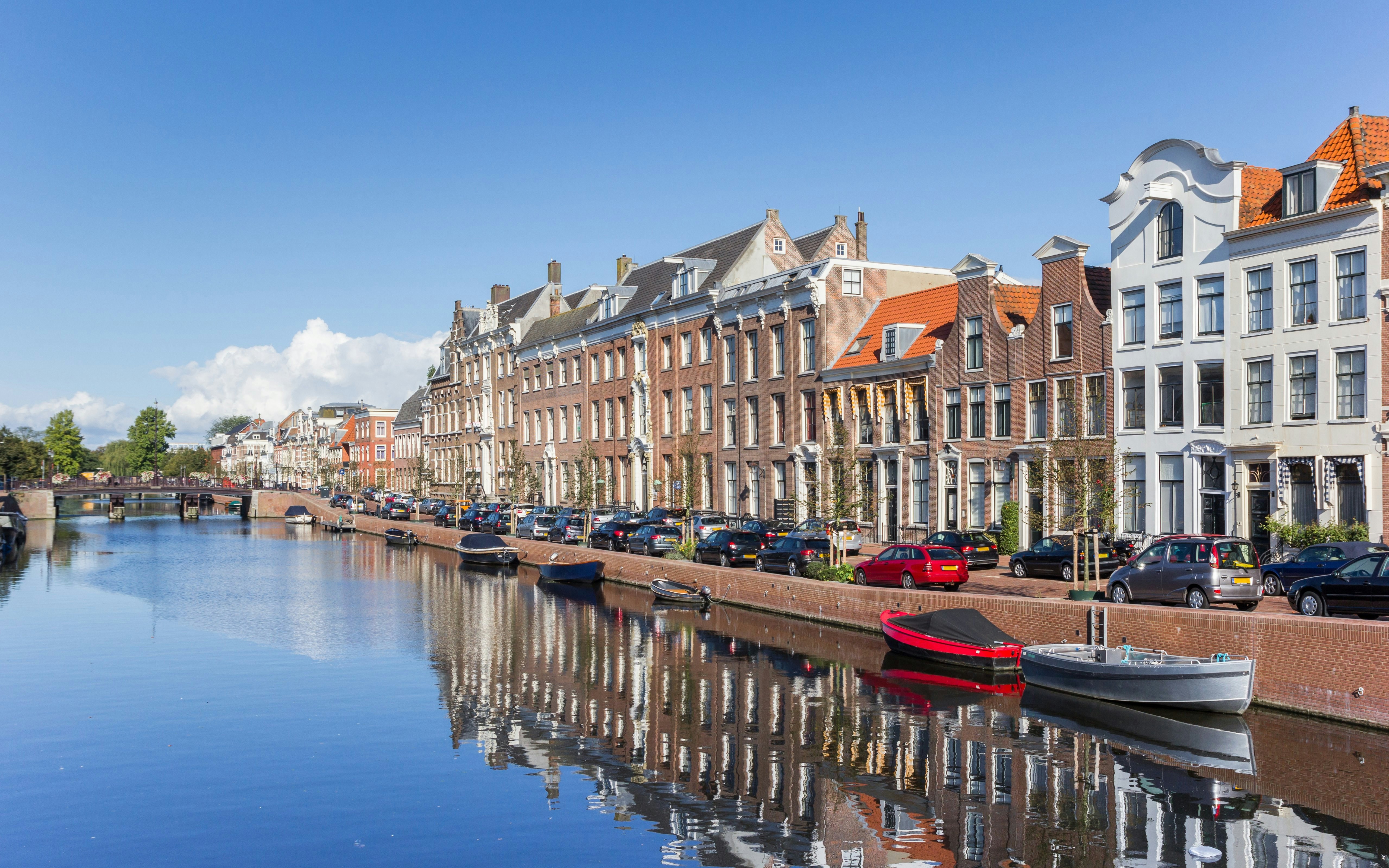 Historic houses along Nieuwe Gracht canal in Haarlem with boats and reflections in the water.