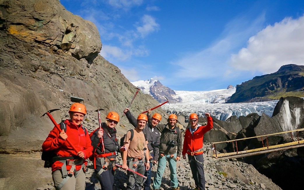 Guests with ice axes on a glacier hike in Skaftafell, Iceland, with a glacier in the background.