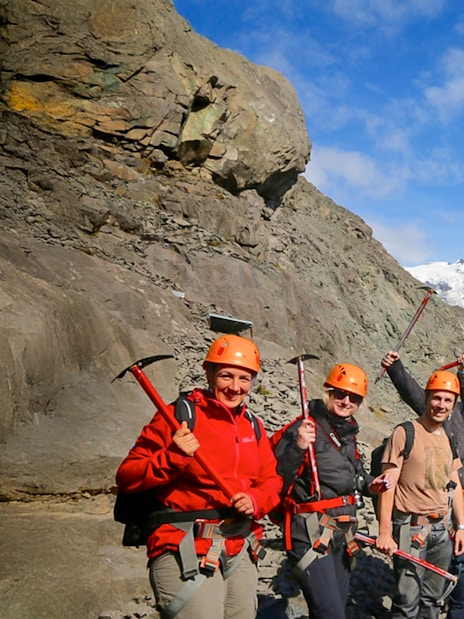 Guests with ice axes on a glacier hike in Skaftafell, Iceland, with a glacier in the background.