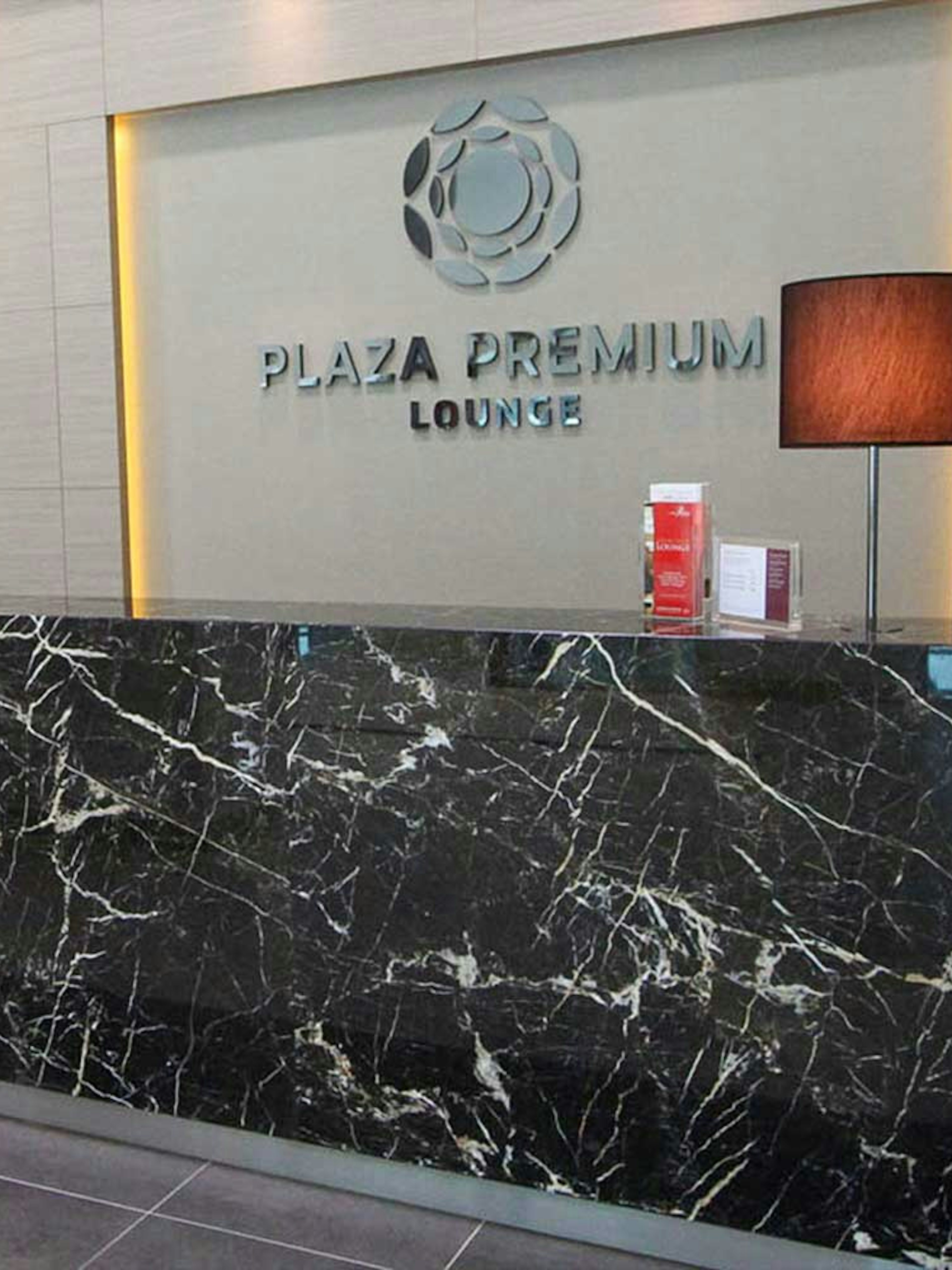 Plaza Premium Lounge reception area with marble desk and lamps.