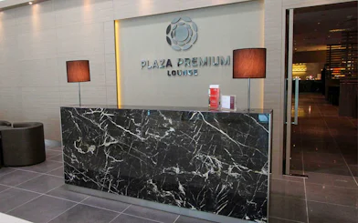 Plaza Premium Lounge reception area with marble desk and lamps.