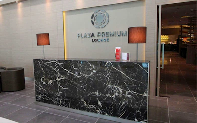 Plaza Premium Lounge reception area with marble desk and lamps.