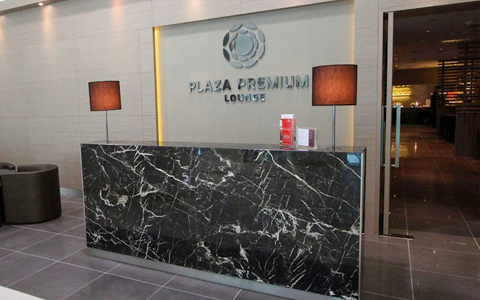 Plaza Premium Lounge reception area with marble desk and lamps.