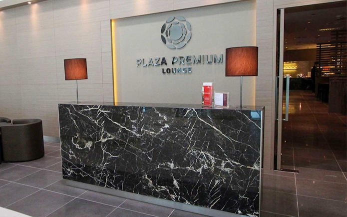 Plaza Premium Lounge reception area with marble desk and lamps.