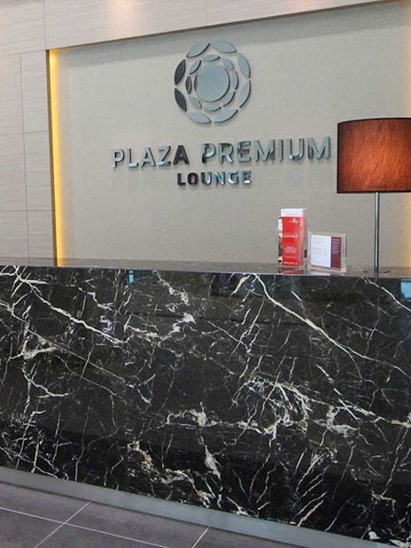 Plaza Premium Lounge reception area with marble desk and lamps.