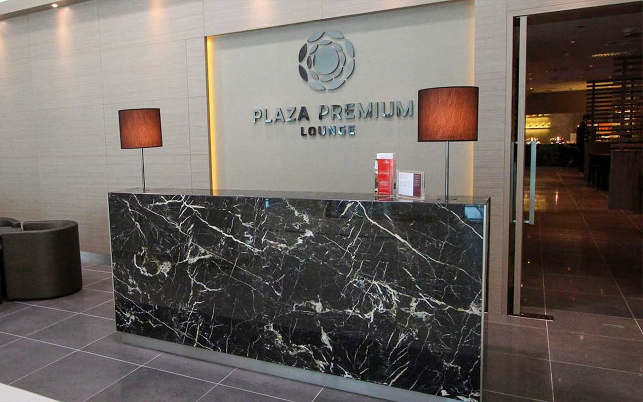 Plaza Premium Lounge reception area with marble desk and lamps.