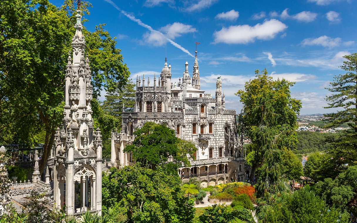 Quinta da Regaleira palace and gardens in Sintra, Portugal, surrounded by lush greenery.