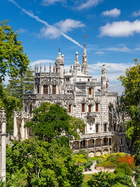 Quinta da Regaleira palace and gardens in Sintra, Portugal, surrounded by lush greenery.