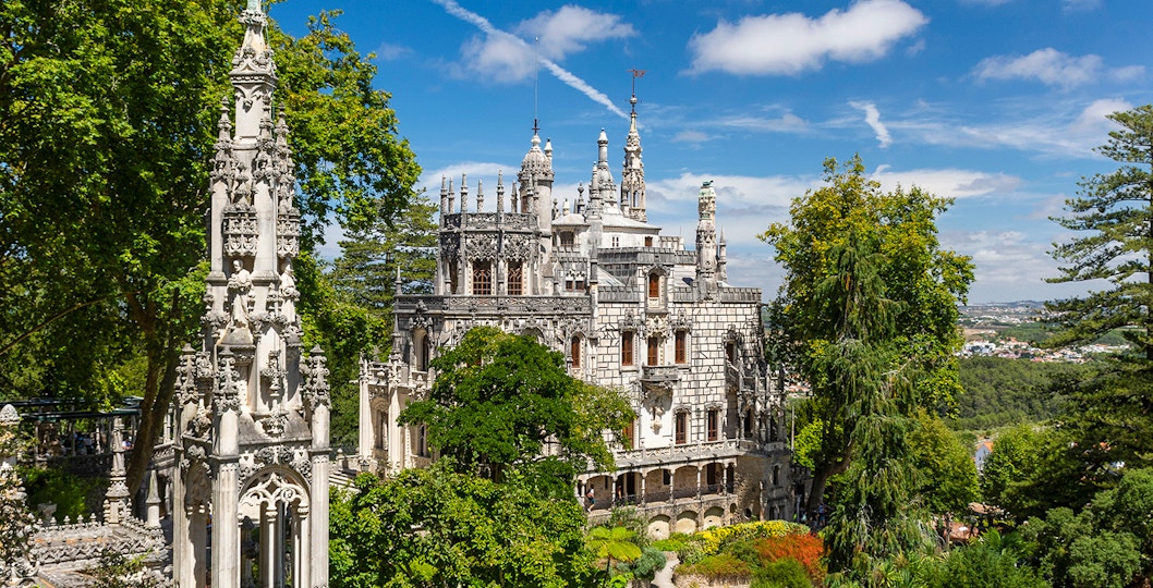 Quinta da Regaleira palace and gardens in Sintra, Portugal, surrounded by lush greenery.