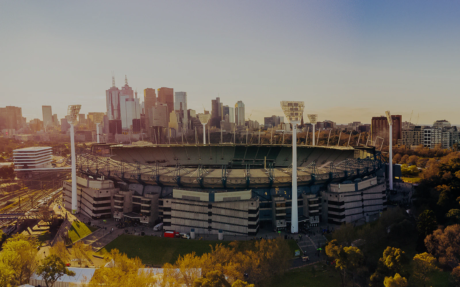Aerial view of Melbourne Cricket Ground with city skyline in the background.