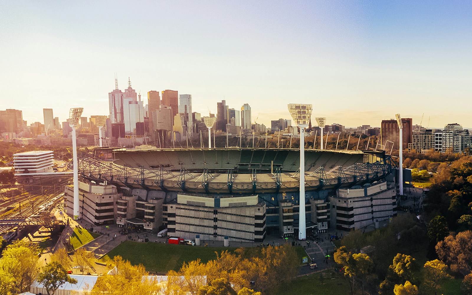Aerial view of Melbourne Cricket Ground with city skyline in the background.