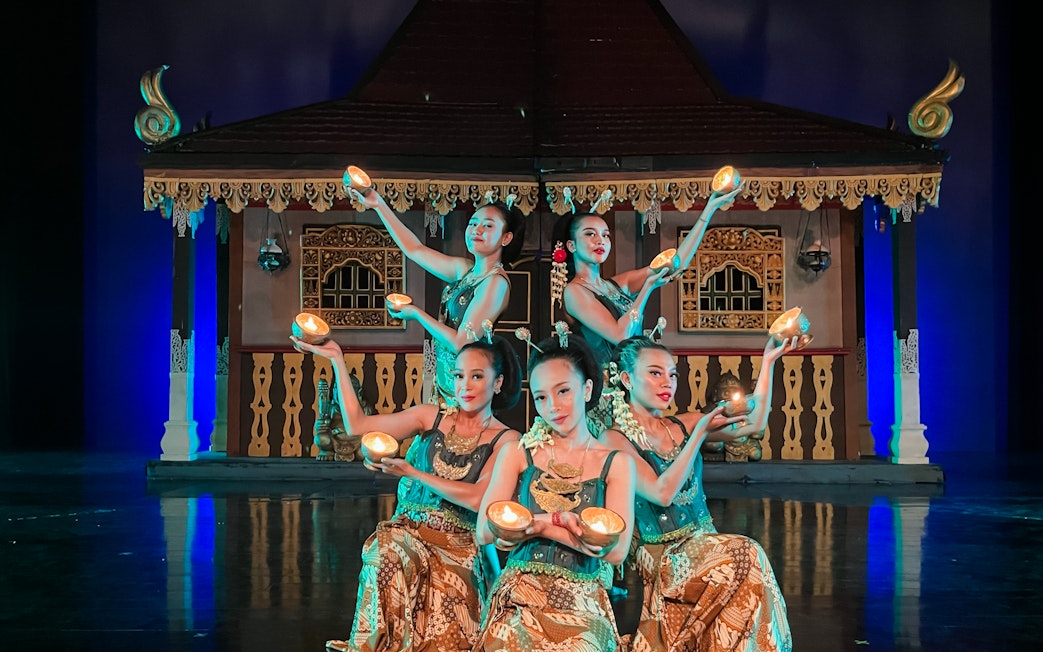 Performers holding lights on stage during the Devdan Show in Bali, showcasing cultural dance.