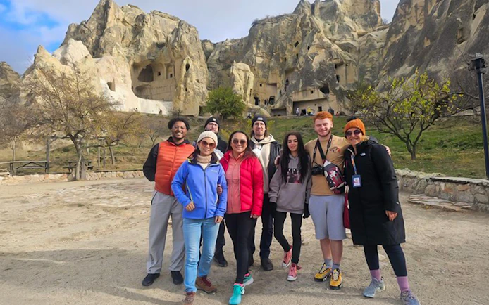 Guests exploring Uchisar Castle in Cappadocia with rock formations in the background.