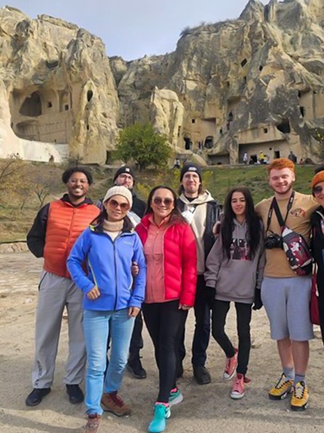 Guests exploring Uchisar Castle in Cappadocia with rock formations in the background.