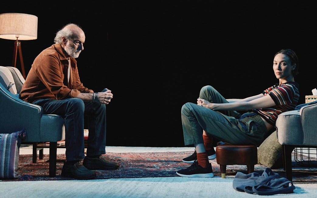Two people sitting in a dimly lit room, engaged in conversation.