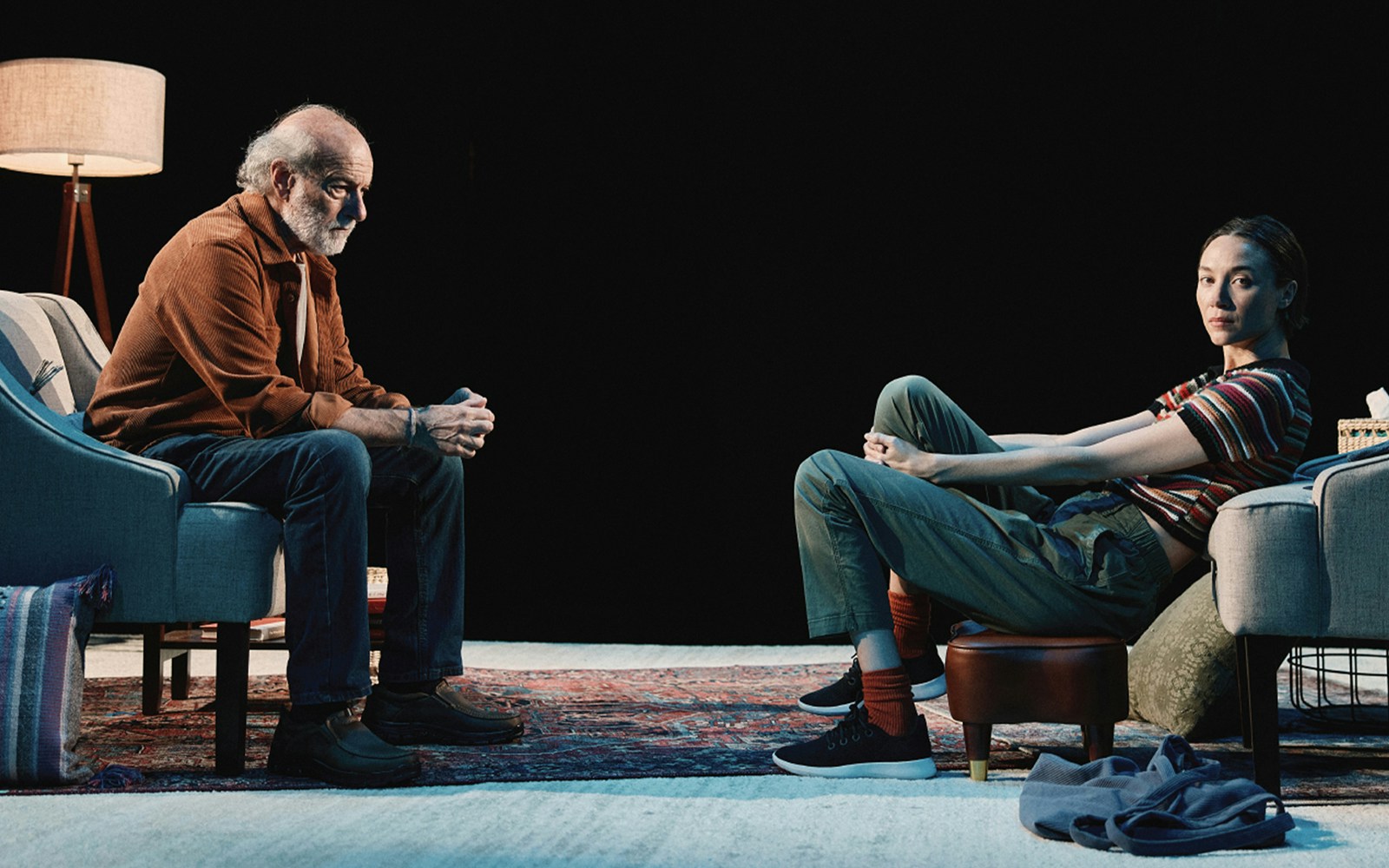 Two people sitting in a dimly lit room, engaged in conversation.