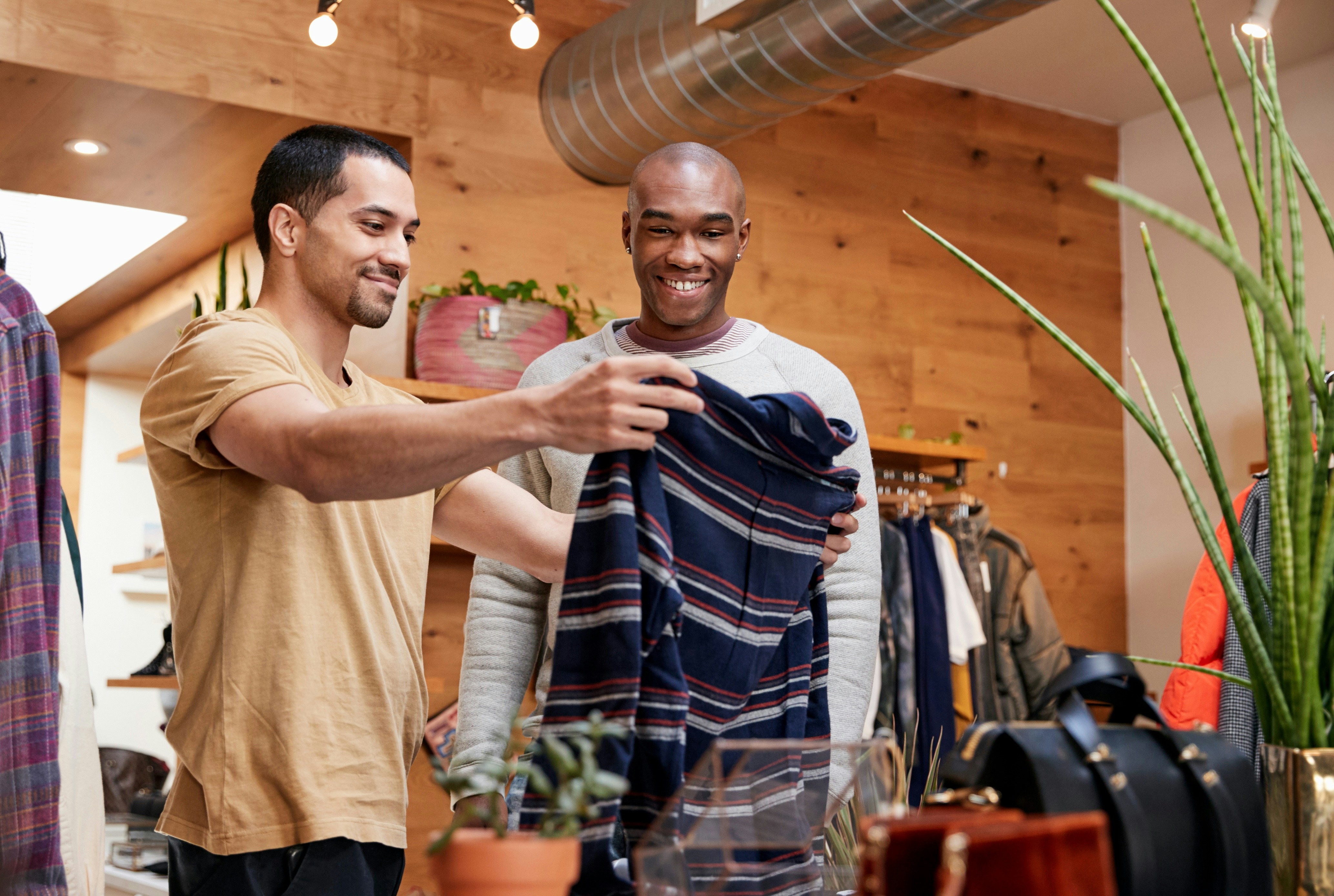 Men shopping for clothes in a boutique, examining a striped shirt.