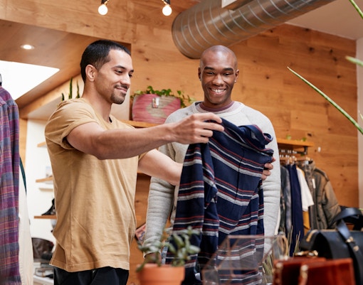 Men shopping for clothes in a boutique, examining a striped shirt.