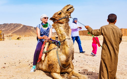 Person riding a camel in Hurghada desert during a quad bike safari tour.