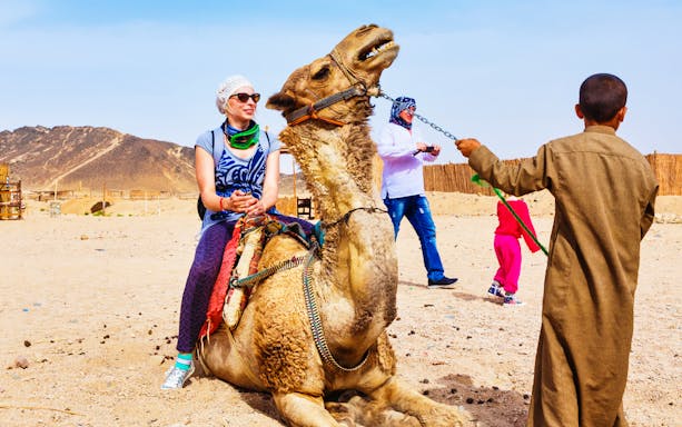 Person riding a camel in Hurghada desert during a quad bike safari tour.